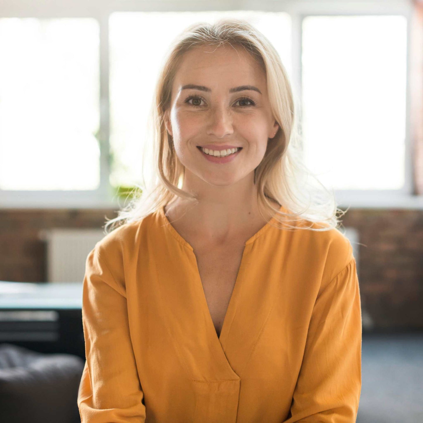 Smiling middle-aged woman in mustard yellow blouse representing health checkup for women over 40 including sangre oculta en heces test